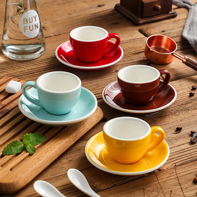 Las tazas multicoloras del café express de la porcelana 75ml con los platillos abultan las fuentes de la cocina