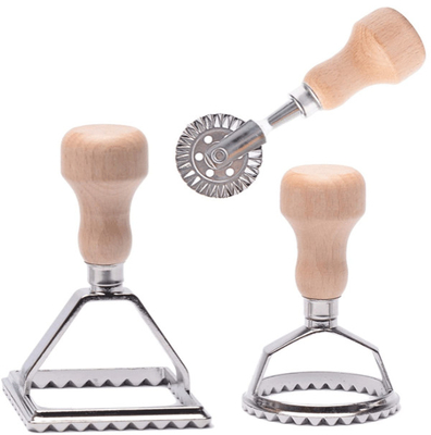 Molde de acero inoxidable de los raviolis con la manija de madera usada para hacer las bolas de masa hervida italianas