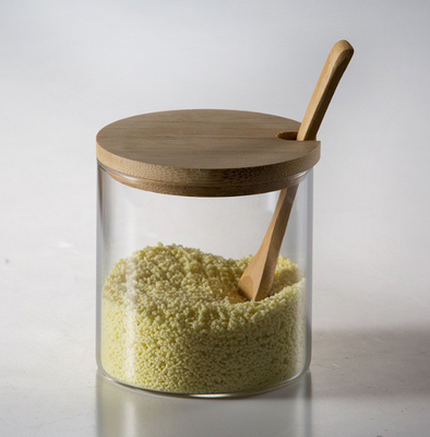 Los envases de aderezo del condimento de cristal abultan los tarros reutilizables de la especia con la cuchara de madera de la tapa