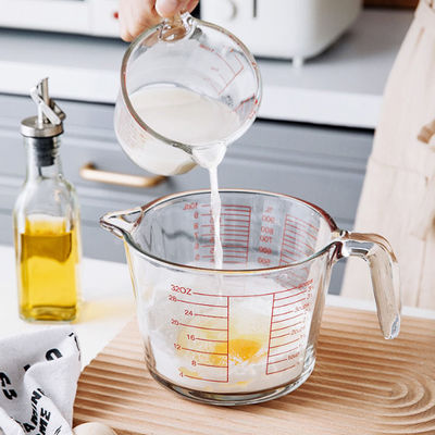 Taza de medición de cristal de la cocina que cuece con los gráficos rojos microonda y horno
