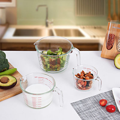 Taza de medición de cristal de la cocina que cuece con los gráficos rojos microonda y horno
