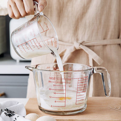 Taza de medición de cristal de la cocina que cuece con los gráficos rojos microonda y horno